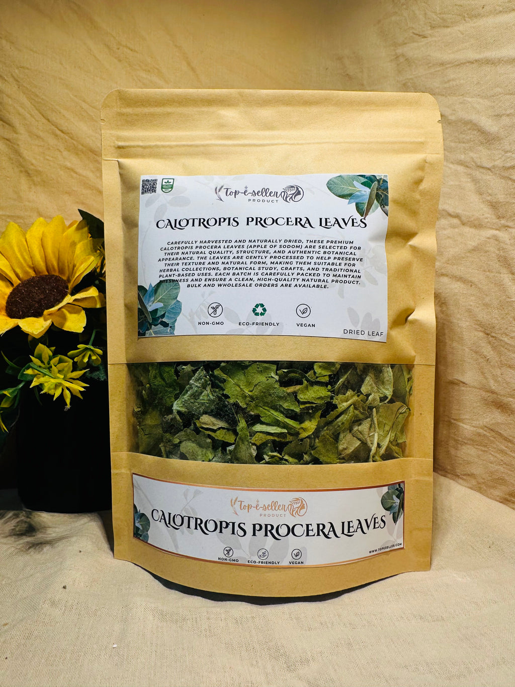 Packaged Calotropis procera leaves with a sunflower in the background on a wooden surface.