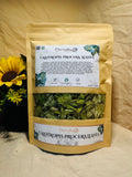 Packaged Calotropis procera leaves with a sunflower in the background on a wooden surface.