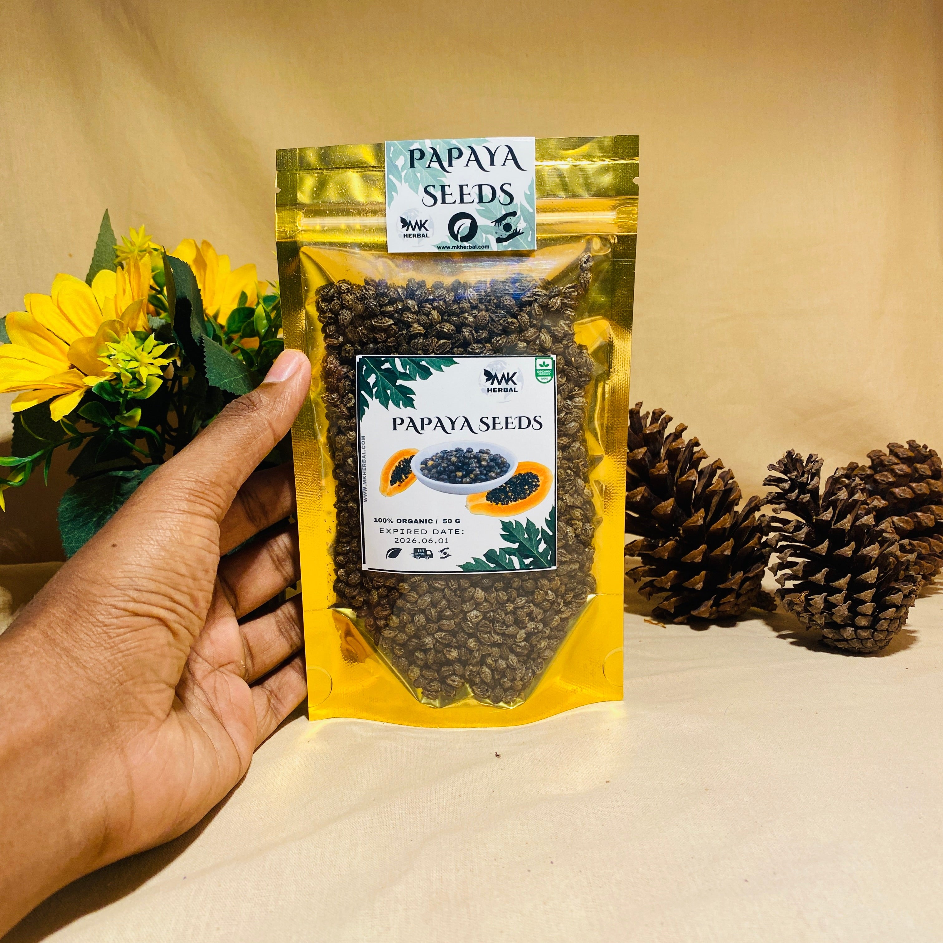 Hand holding a package of papaya seeds with a beige background